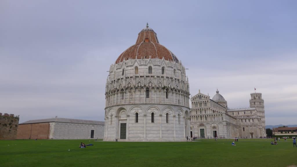 Photo of Cathedral Square in Pisa with it's lush green grass and beautiful stone structures.
