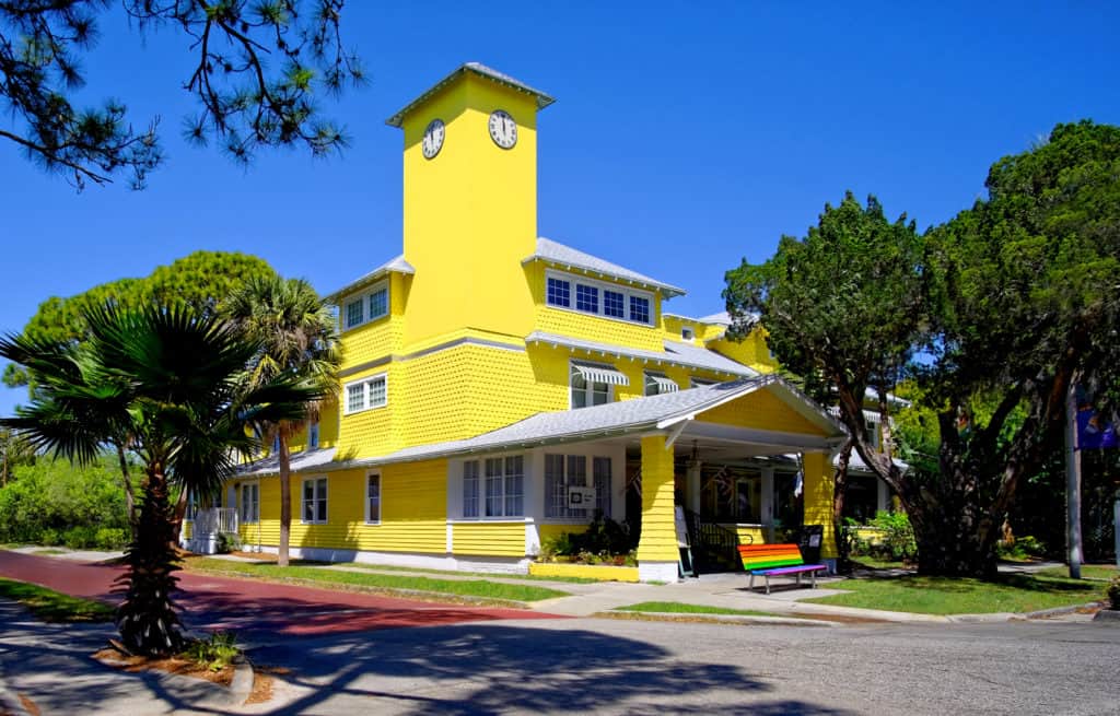 best hotels in gulport - Peninsula Inn - bright yellow exterior on the brick paved roads