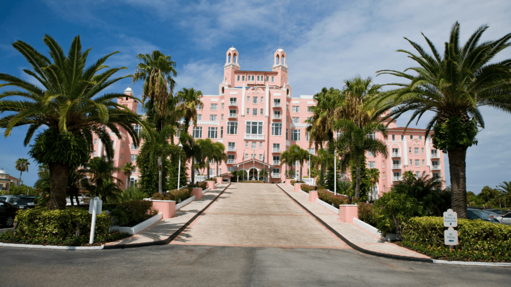 Pink hotel with a grand driveway that elevates the second floor of the hotel. 