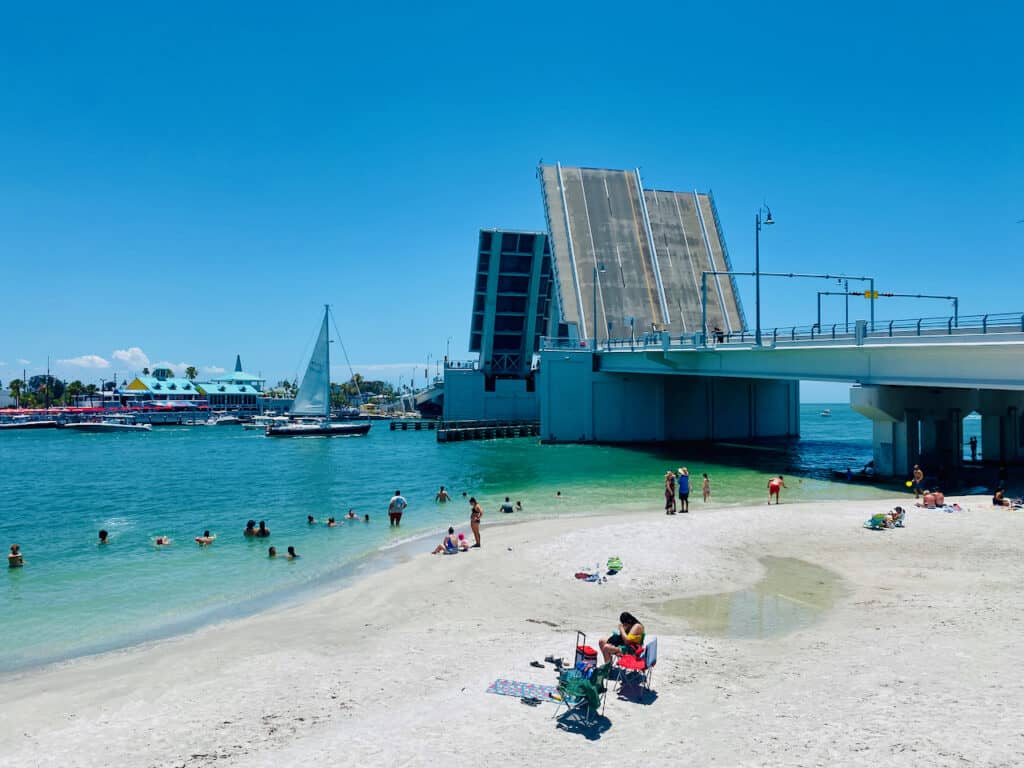 Madeira Beach photo from John's Pass shows the bridge and people sitting on the beach.