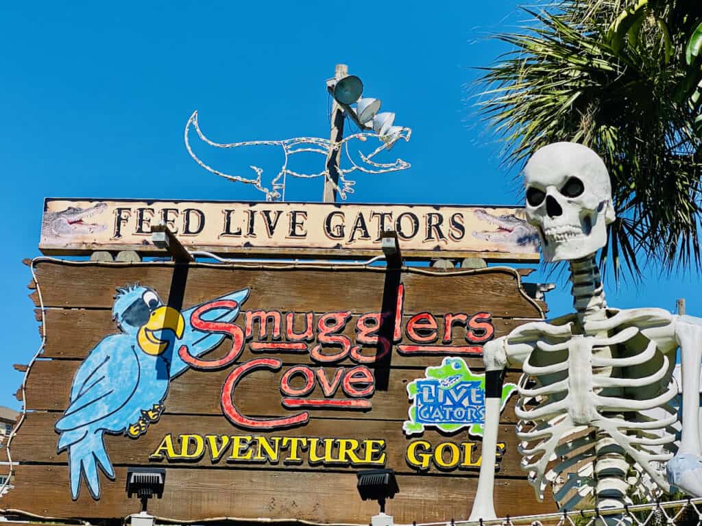 Smugglers Cove Adventure Golf showing sign decorated in skulls and gators.