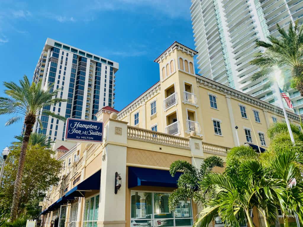 The Hampton Inn Downtown St Pete is one of our favorite hotels in downtown st pete for kids and family friendly.  Photo shows lots of thinks nearby from the outside of the hotel - shops, and businesses and a park across the street. 