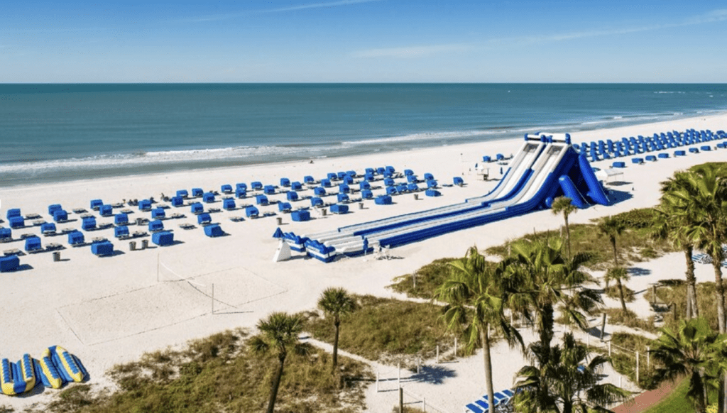 Tradewinds Resort on St Pete Beach with big blue slide in the distance with beach chairs. One of the most kid friendly hotels in st pete beach.