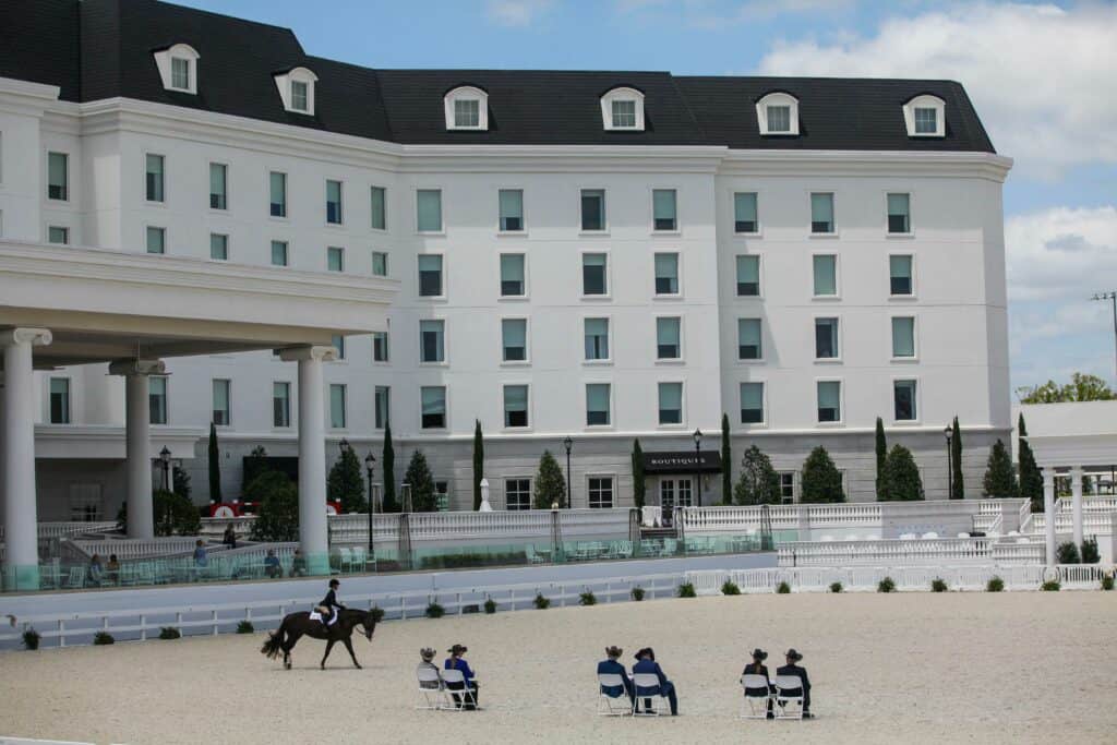 World Equestrian Center is truly one of the top things to do in Ocala with a state of the art exhibitions, luxury hotel, restaurants and shopping.  Photo is of the horse arena with english rider competing with judges watching in their seats.