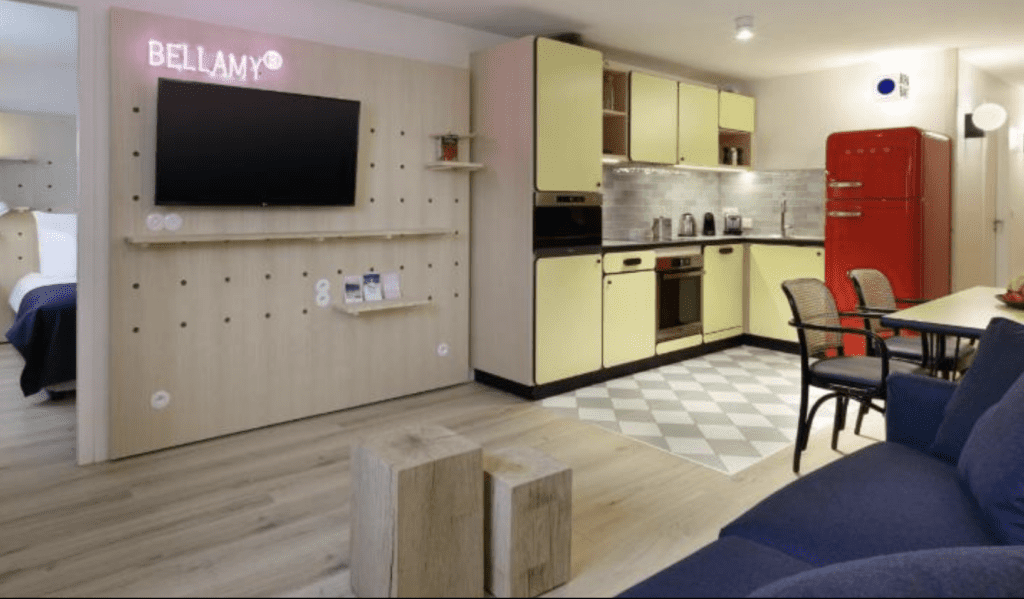 Appart’hotel Bellamy shows the spacious kitchen in their apartments and living room with TV. For space and affordability, it is one of best places to stay in Chamonix France.