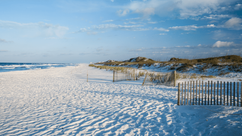 Grayton Beach with beautiful sand dunes and fence along the shore.