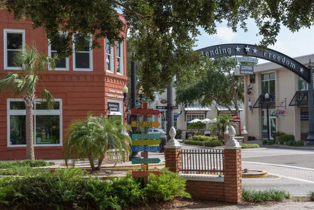 Defending Freedom arch in downtown Dunedin hovers above the street. The brick buildings and water in the distance, makes this charming town feel quaint.