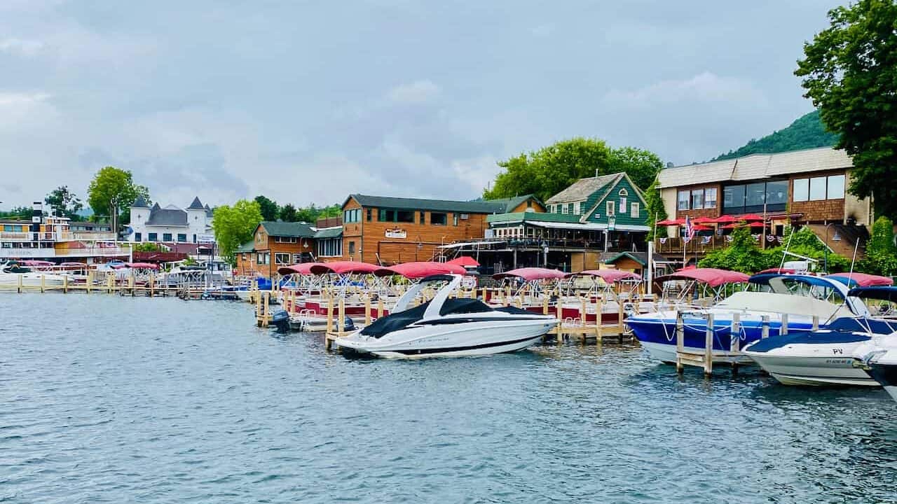 Lake George in the summer has lots of boats on the shoreline next to restaurants and bars