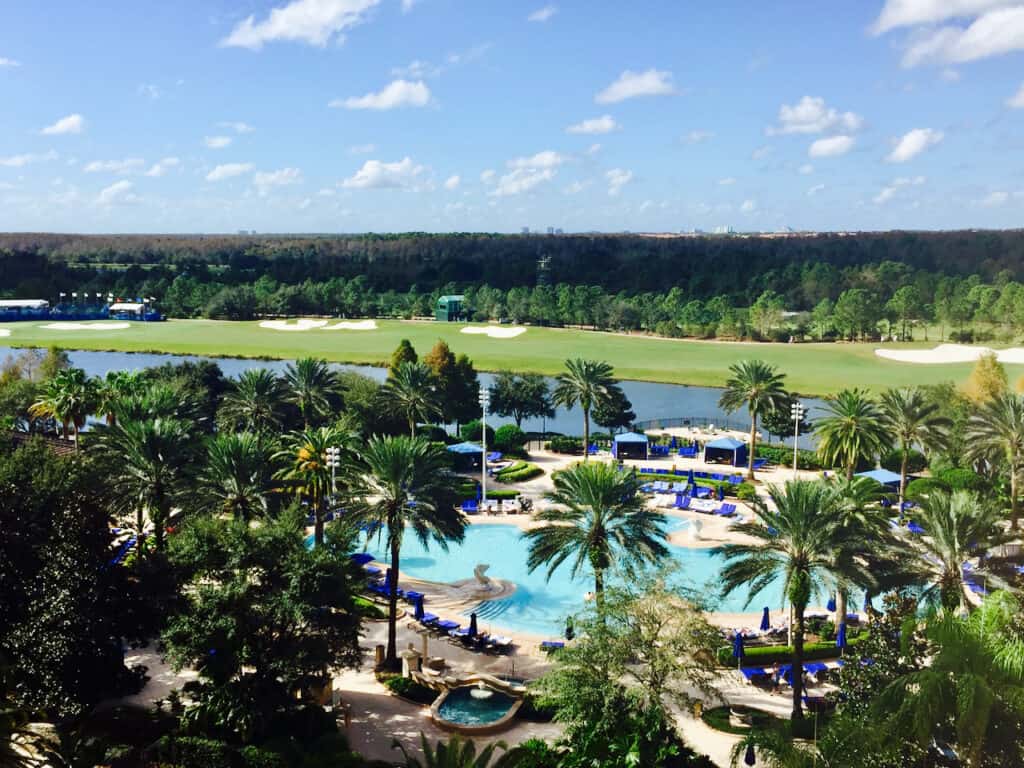 Orlando vacation pool resort surrounded by palm trees and golf course in the distance