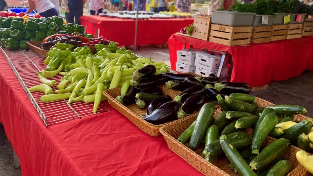 Farmers Market photo showing eggplant, peppers, and zucchini 